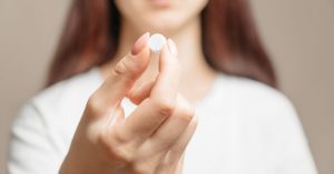 woman holding a pill in her fingers