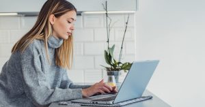 young woman sitting at a table with her laptop